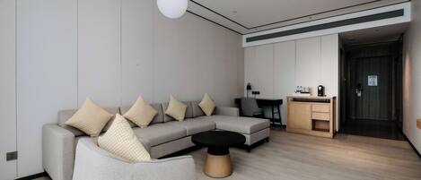 Una sala moderna con un sofá seccional, una mesa de centro redonda y un comedor con un mueble bajo.