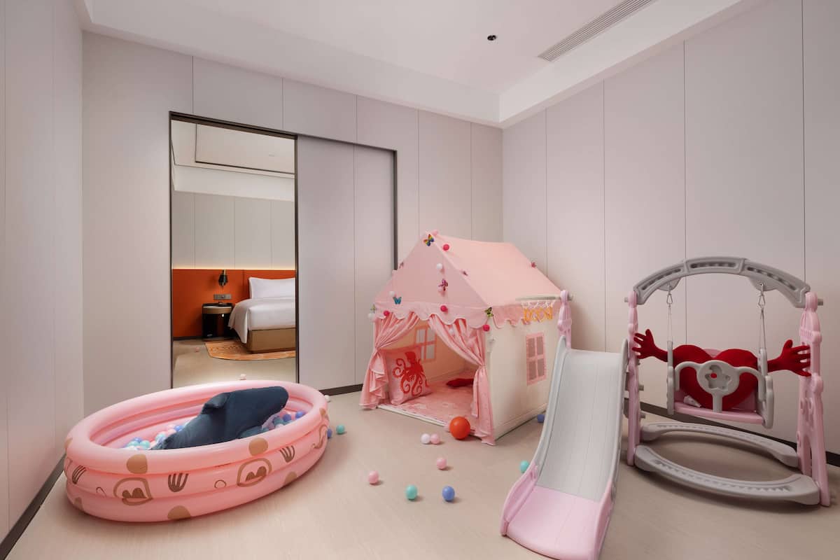 A child's play area with a pink playhouse, a slide, and a swing set.