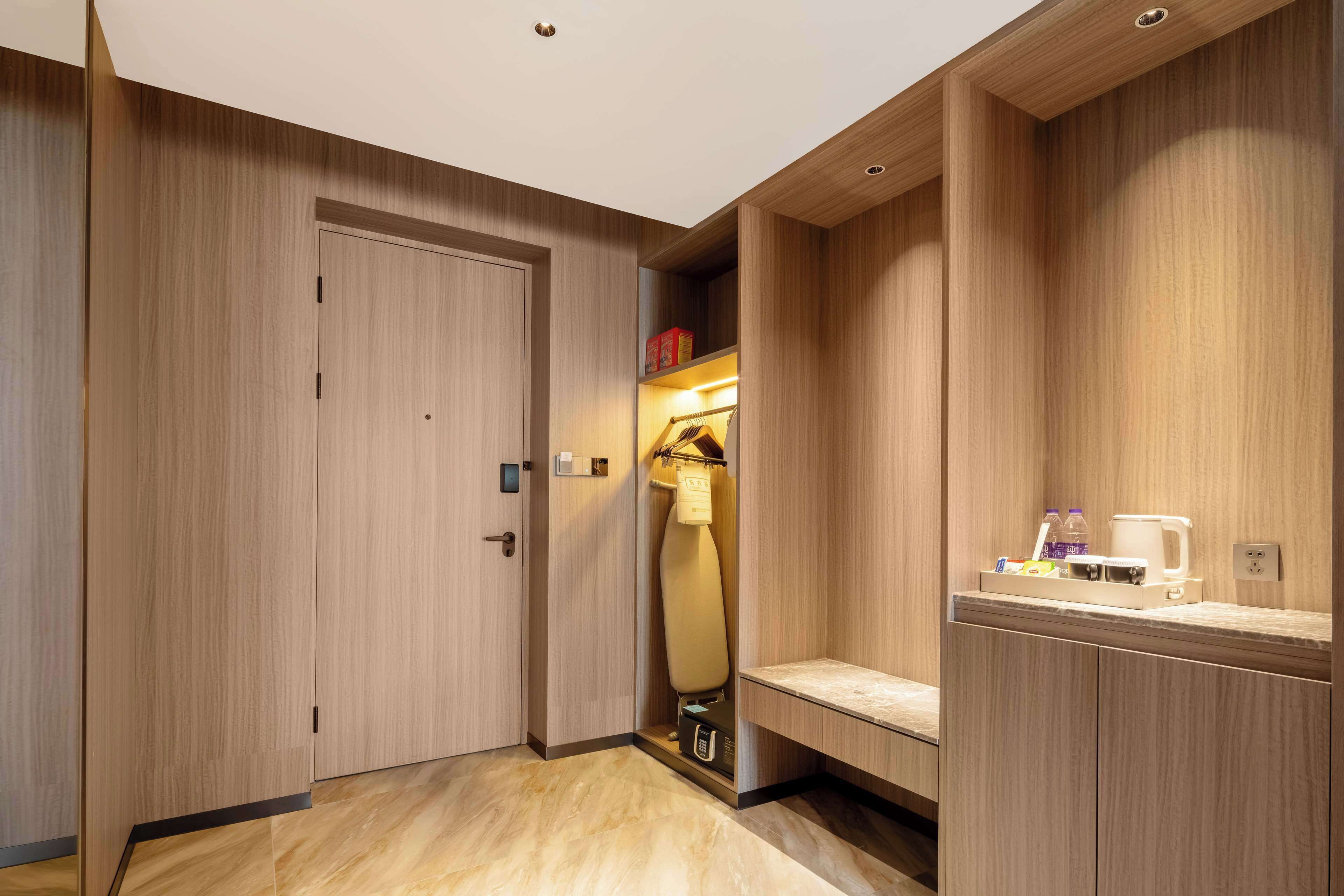 A modern bathroom with a wooden vanity, a towel rack, and a small shelf with toiletries.