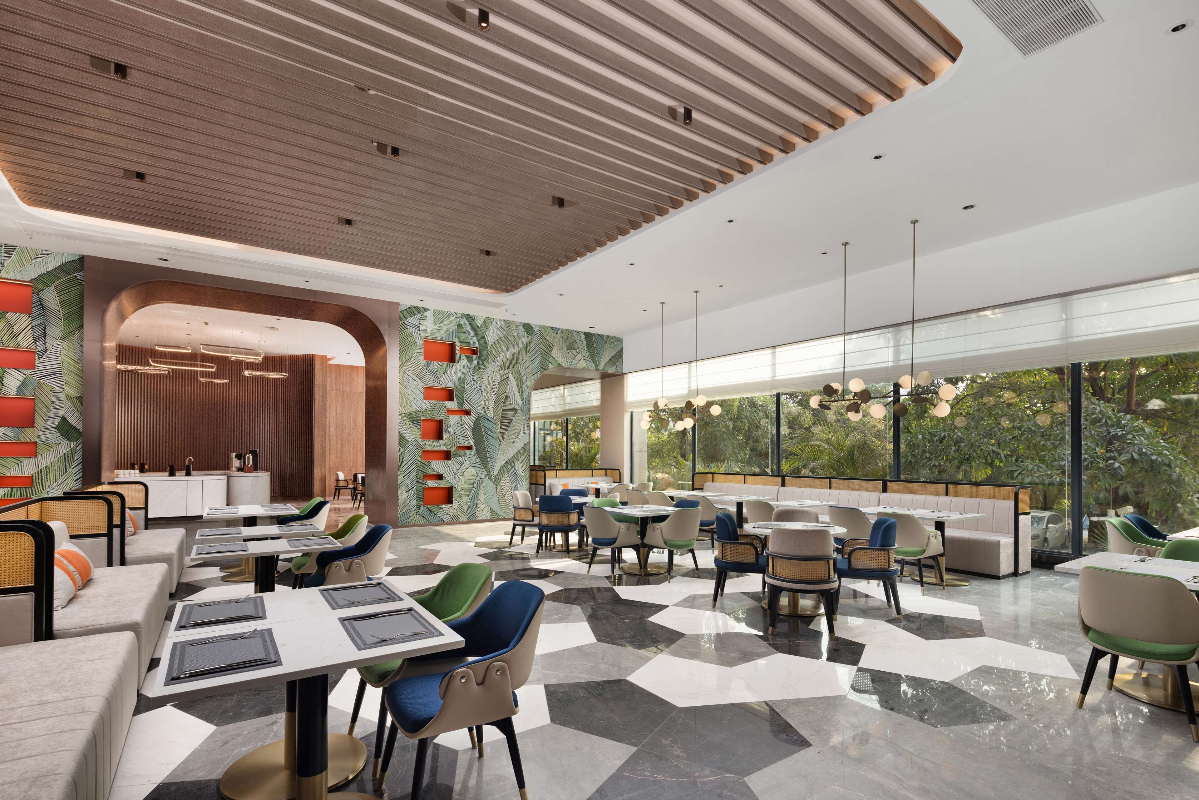 A modern restaurant with a checkered floor, various seating arrangements, and a view of greenery through large windows.