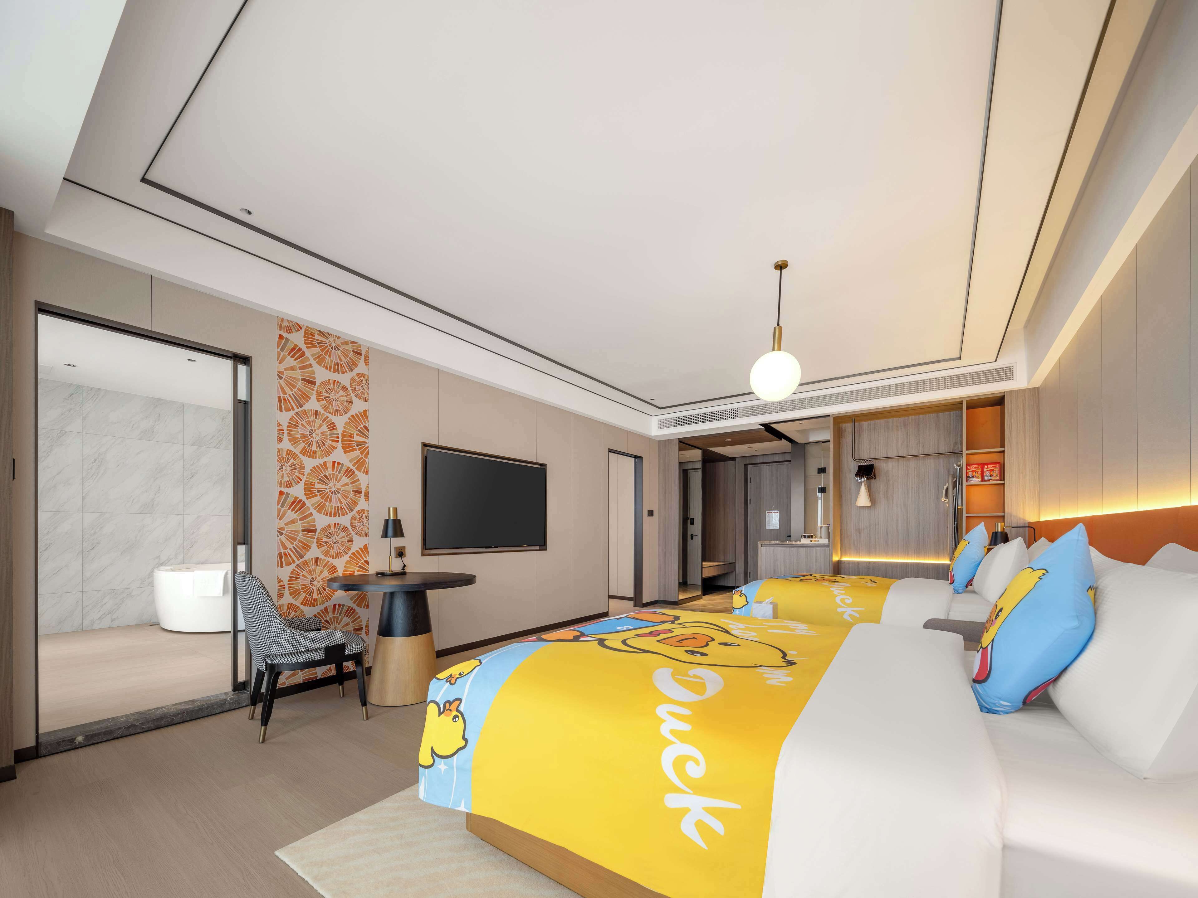 Una habitación de hotel moderna con una cama grande, un televisor, un escritorio y una silla.