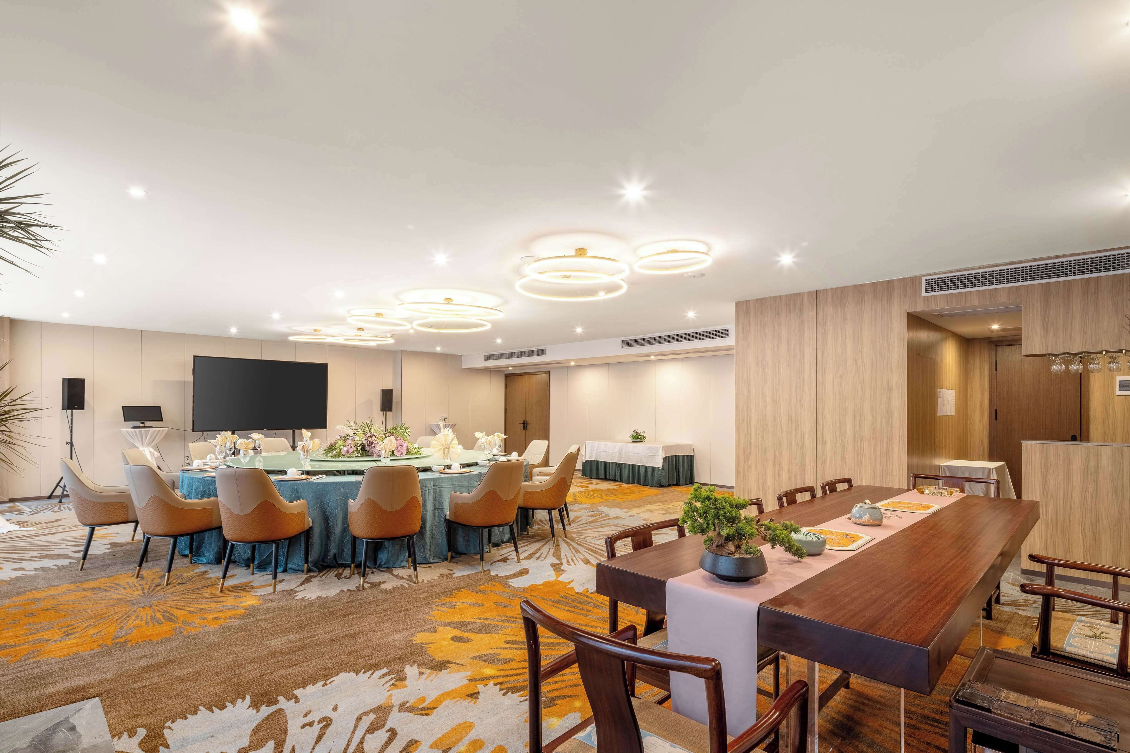 Un salón de conferencias con una mesa larga, varias sillas y una pantalla de televisión.