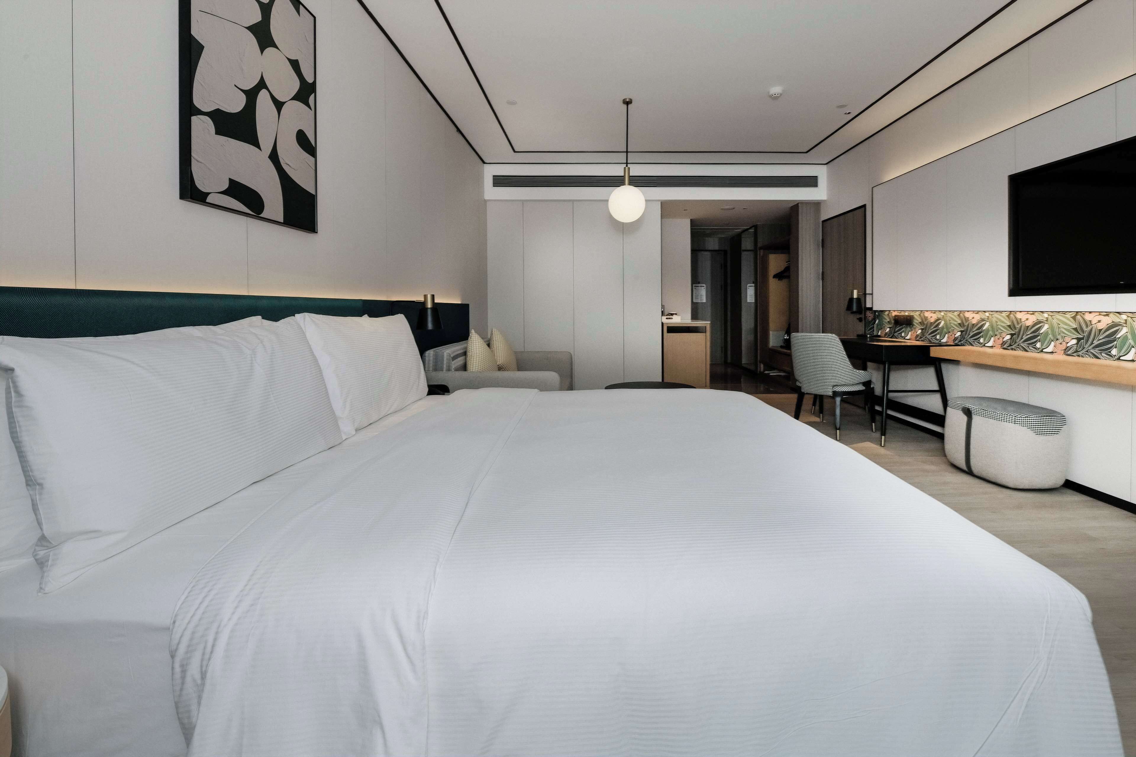 Una habitación de hotel moderna con una cama grande, un escritorio, una silla y un televisor.