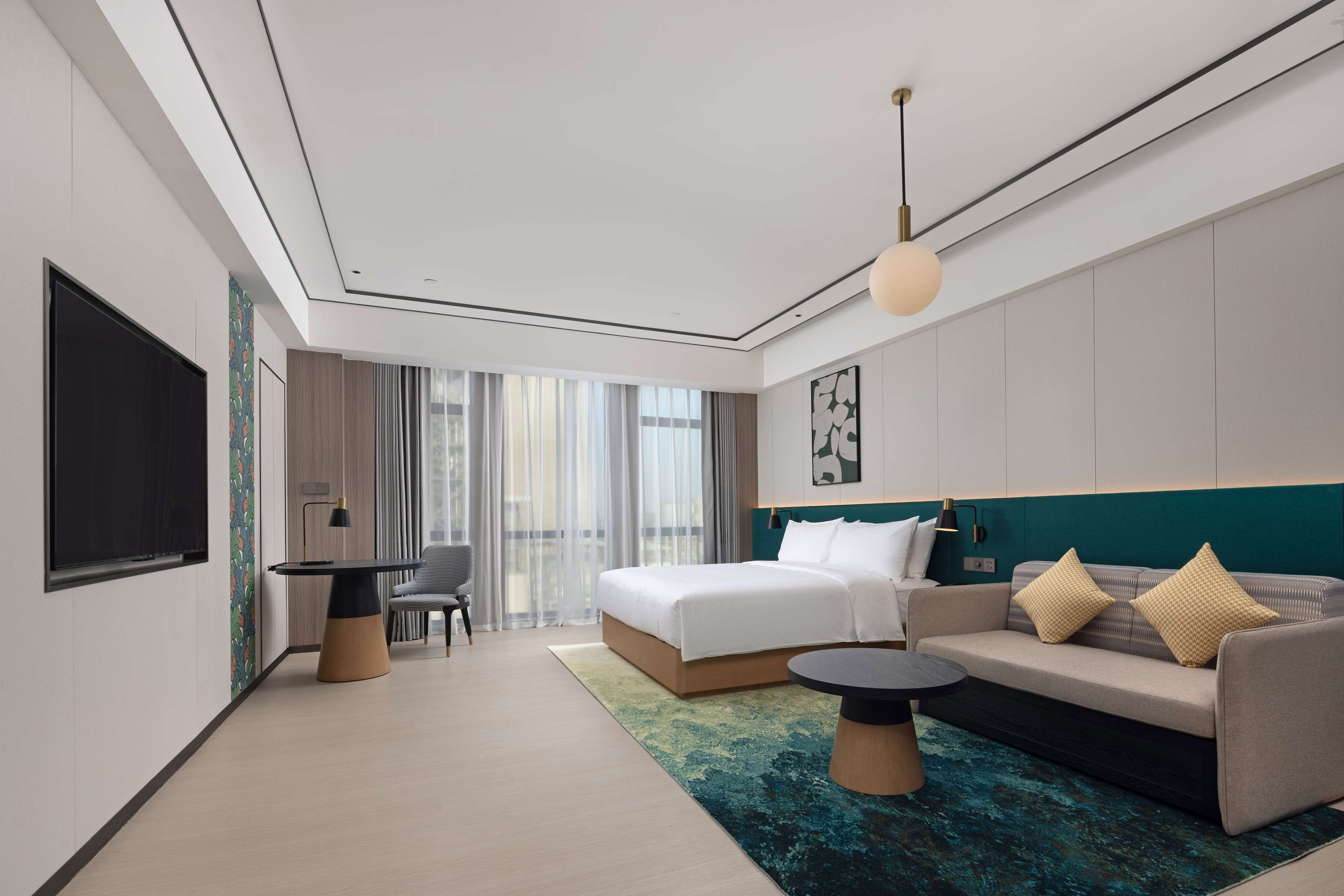 Una habitación de hotel moderna con una cama grande, un sofá, un escritorio y una televisión.