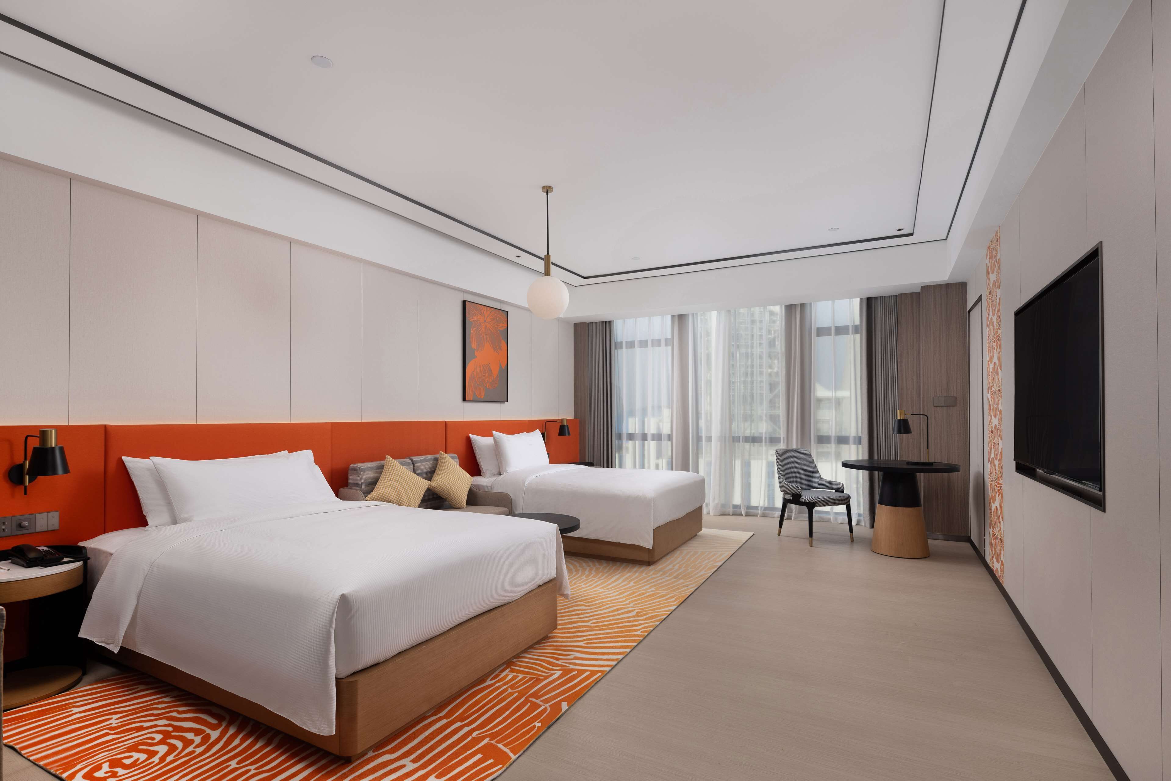 A modern hotel room with two beds, a desk, and a TV.