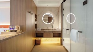 Een moderne badkamer met een houten wastafelmeubel, een marmeren wastafel en een douchecabine van glas.