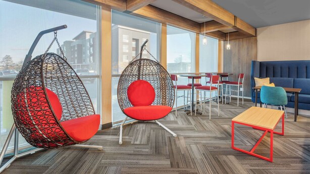 A modern lounge area with hanging chairs, a sofa, and a small table.