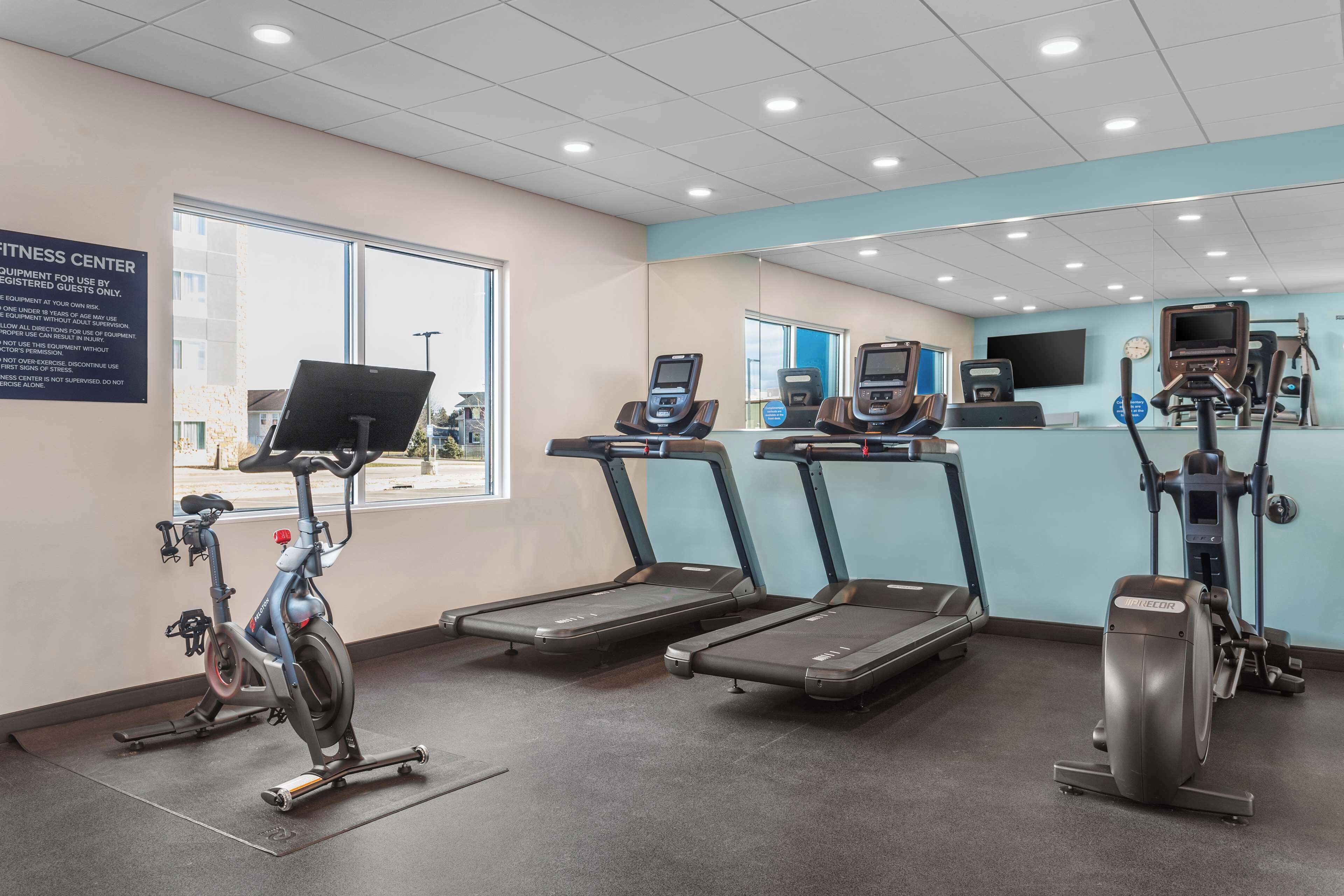 Un gimnasio con cintas de correr, elípticas y una bicicleta estática.