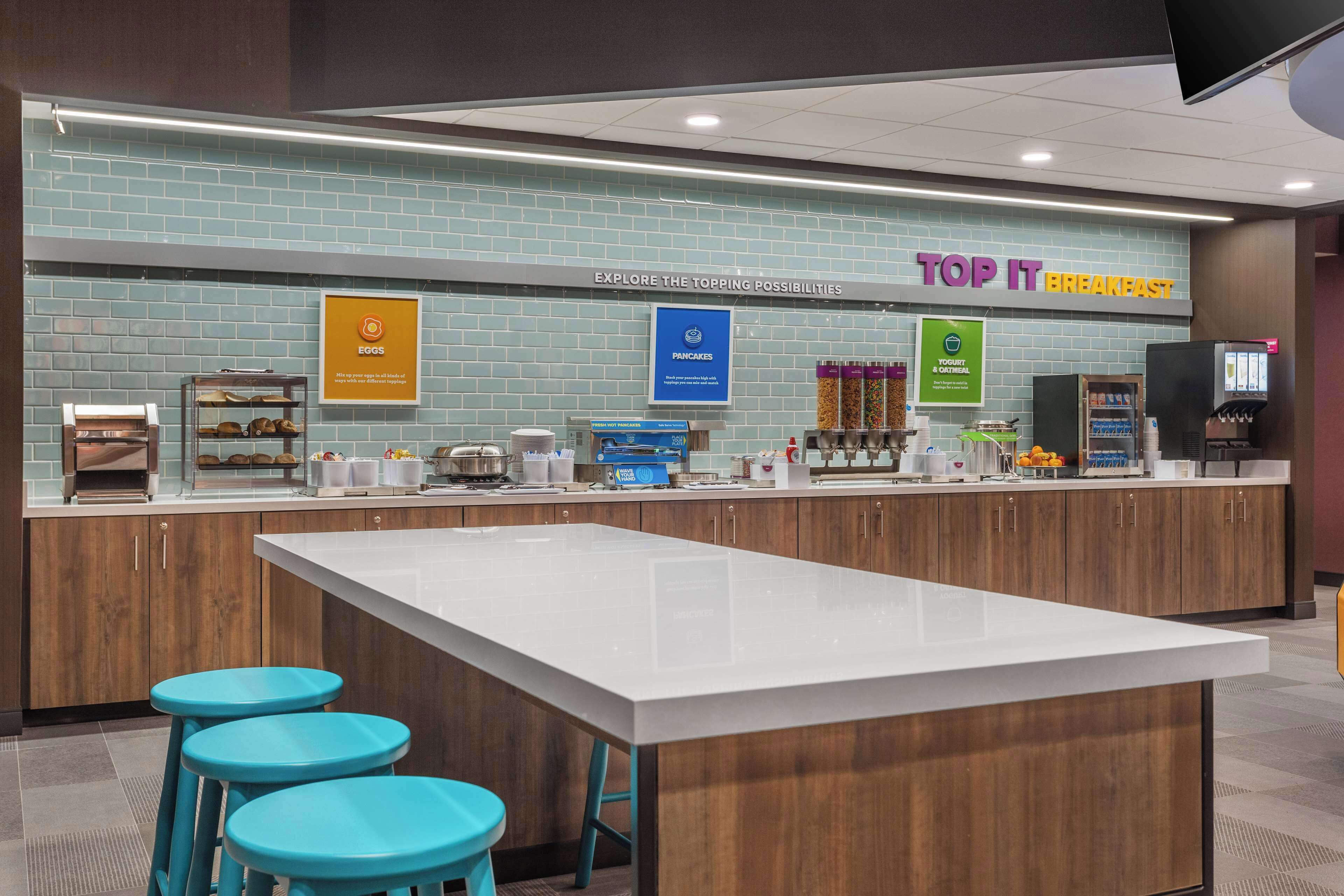 A breakfast area with a counter, stools, and various food display signs.