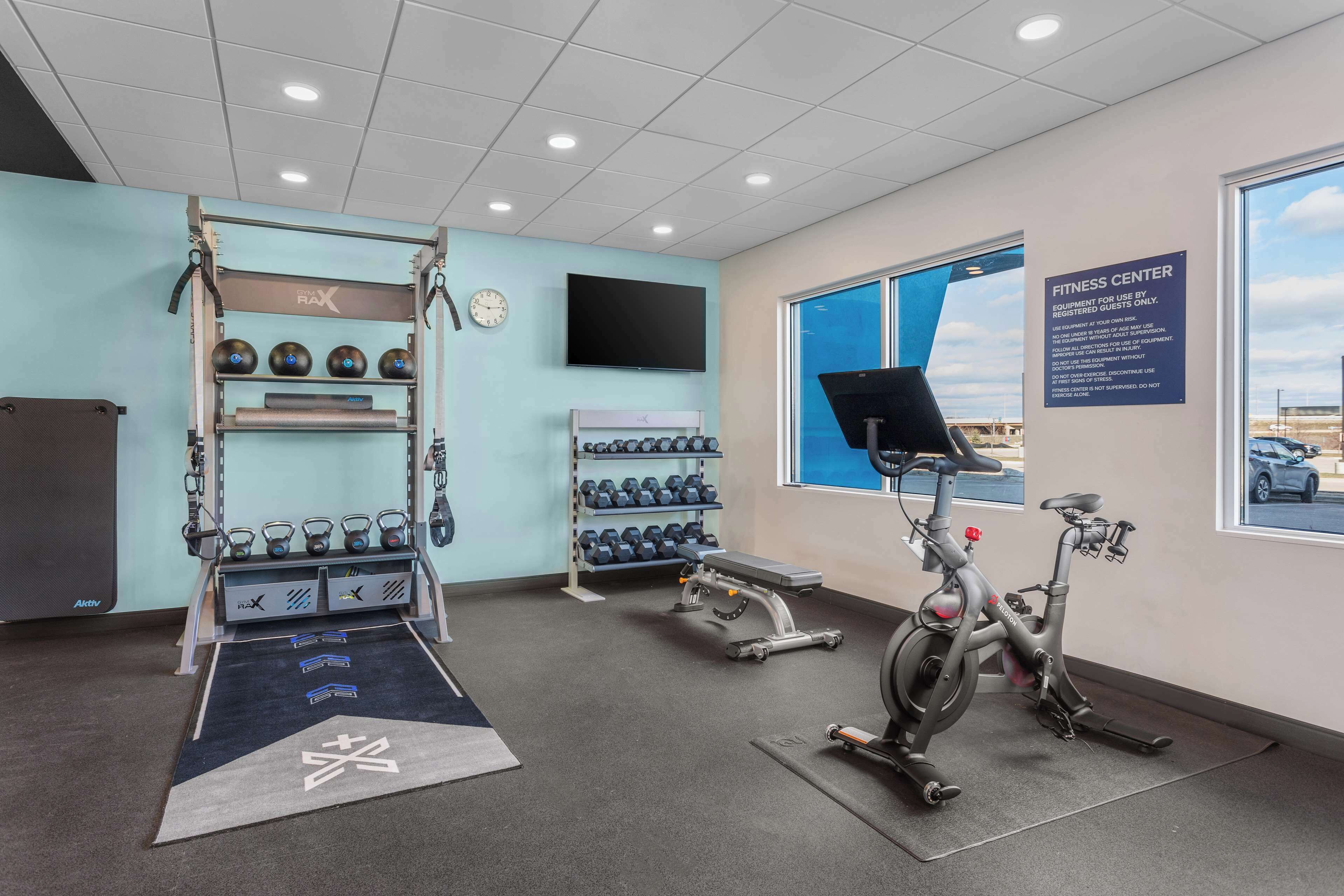 A fitness center with exercise equipment, a treadmill, and a wall-mounted TV.