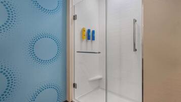 A shower area with a glass door, a towel rack, and two toiletries on the wall.
