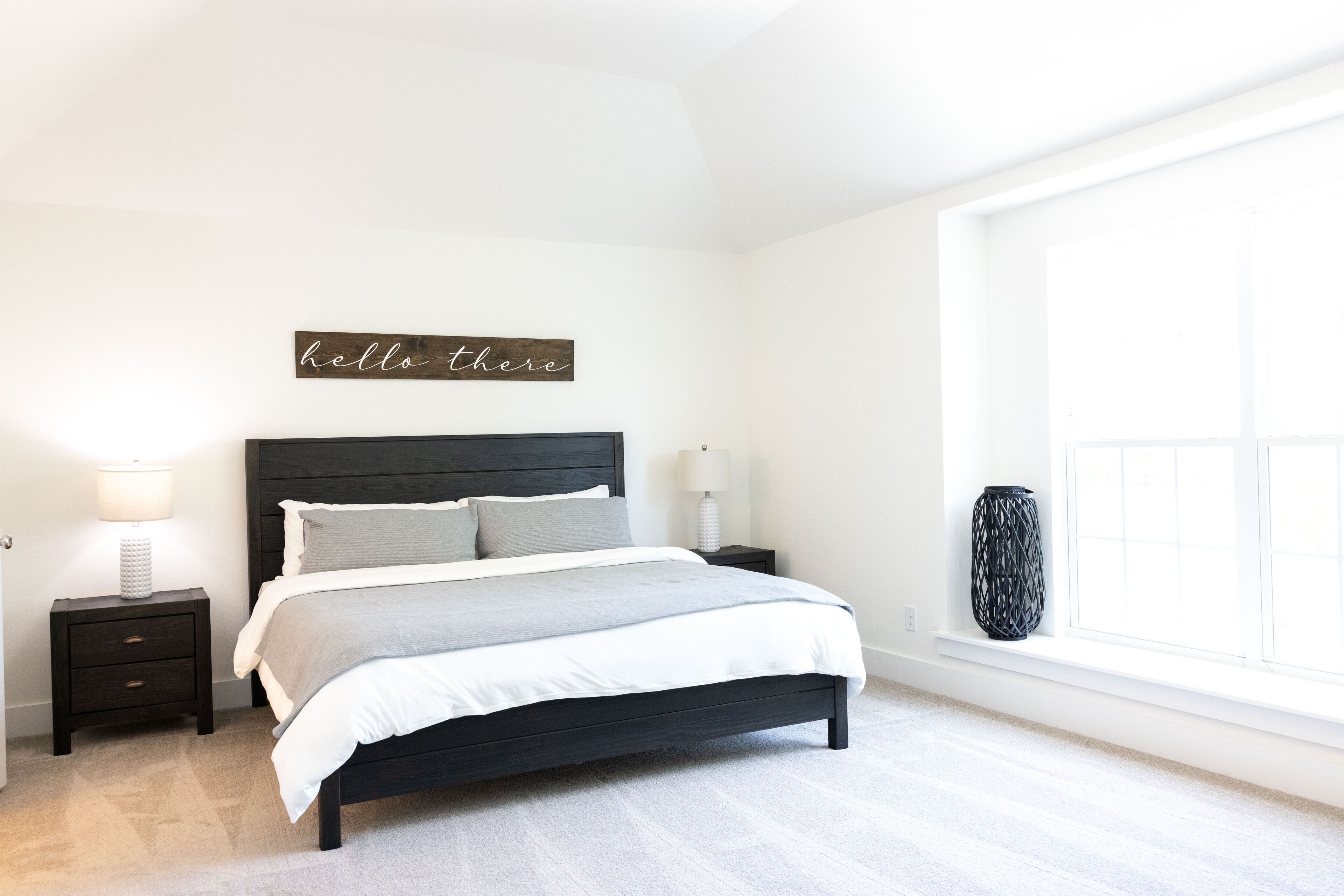 A bedroom with a bed, nightstands, a lamp, a vase, and a window.