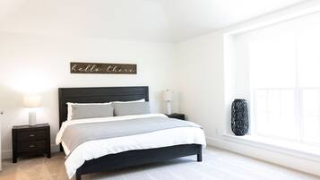 A bedroom with a bed, nightstands, a lamp, a vase, and a window.