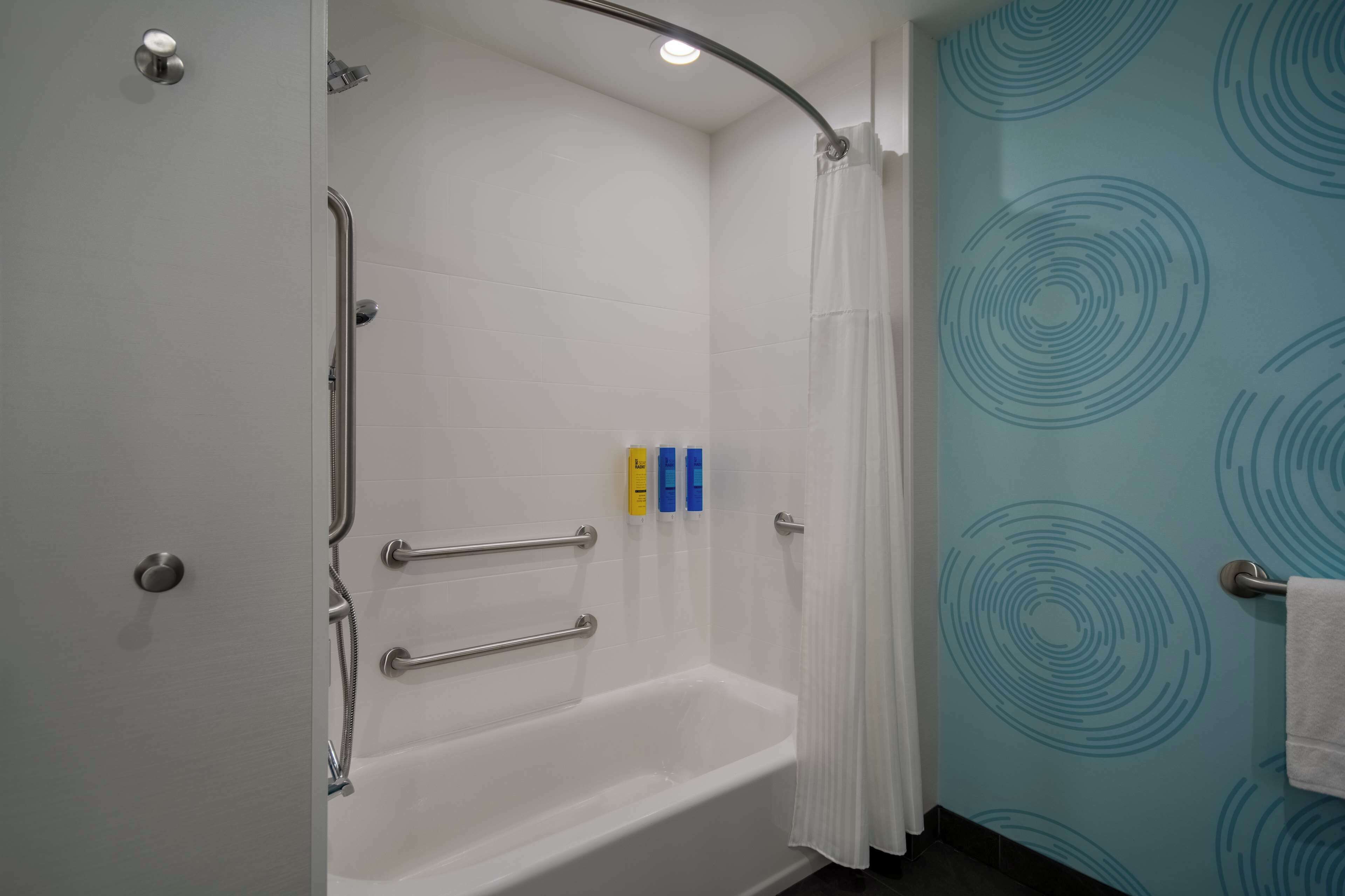 A bathroom with a white bathtub, a shower with a glass door, and a towel rack.