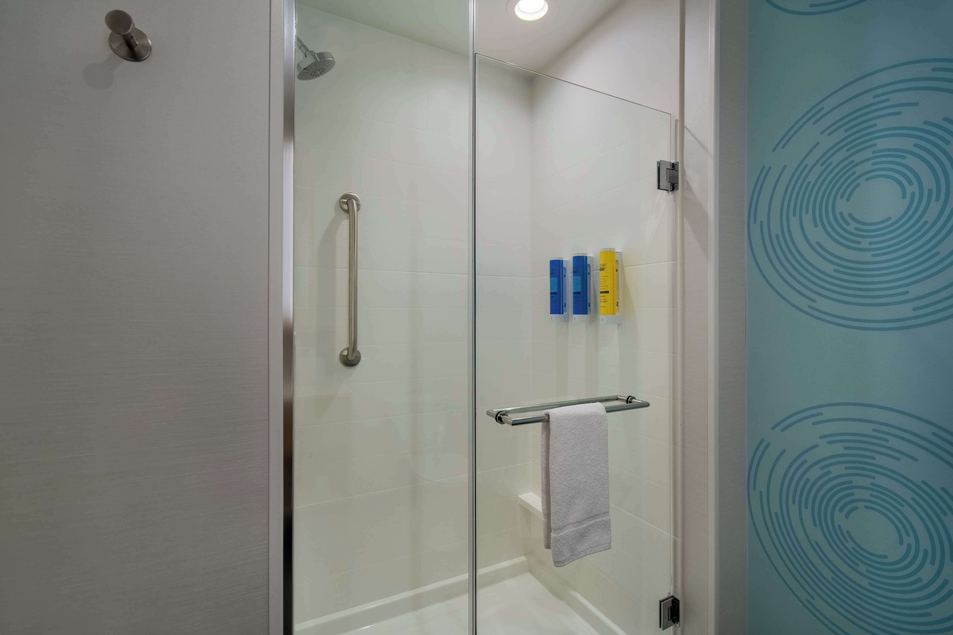 Une salle de bain moderne dotée d’une cabine de douche en verre, d’une porte en verre et d’un porte-serviettes avec une serviette.