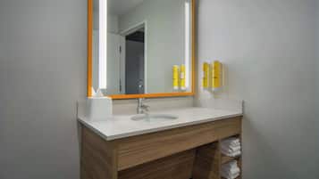 A modern bathroom with a white sink, wooden vanity, and a large mirror with an orange frame.