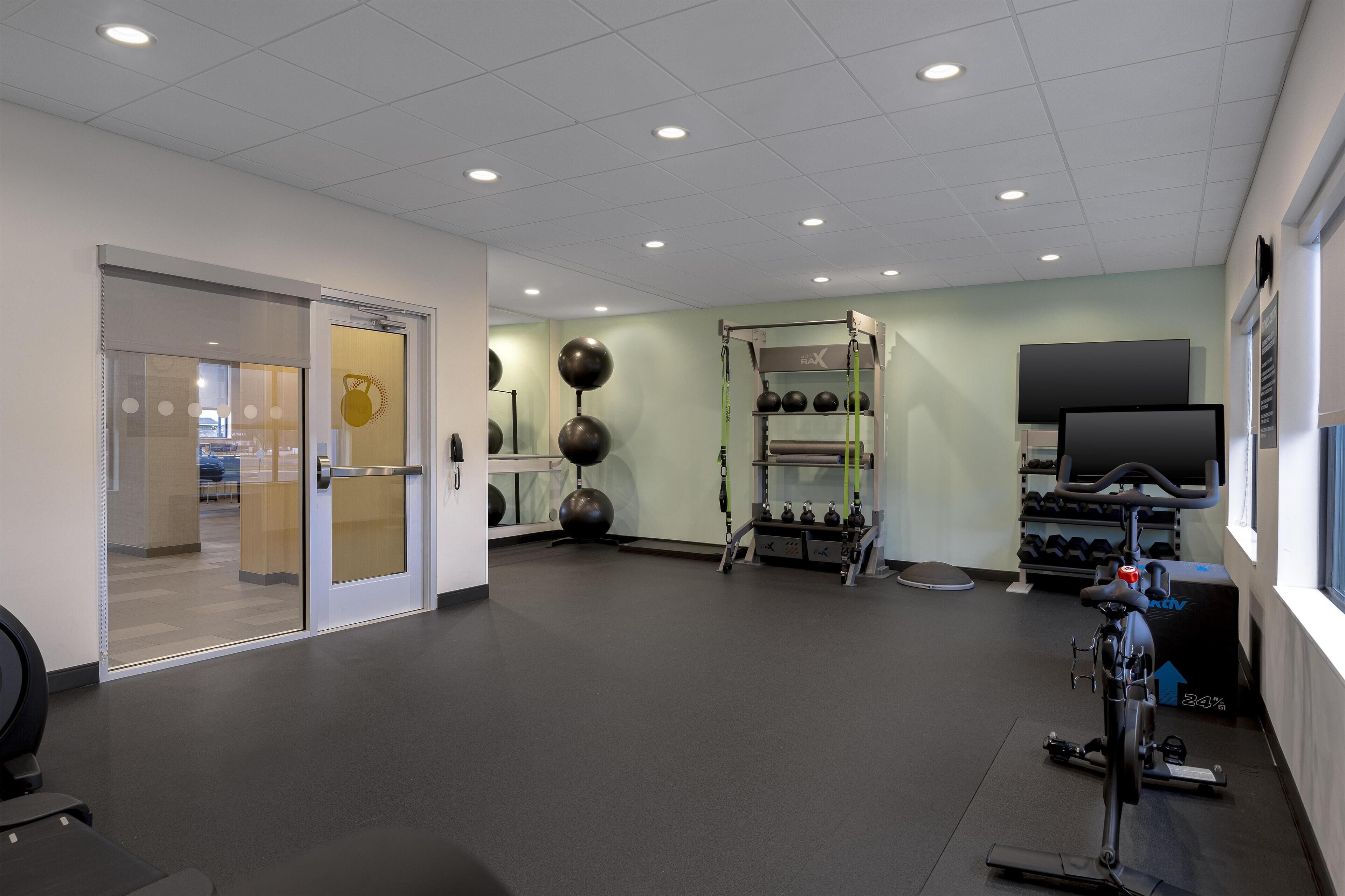 A gym with exercise equipment, a television, and a door leading to another room.