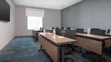 A conference room with multiple tables, chairs, and water bottles.