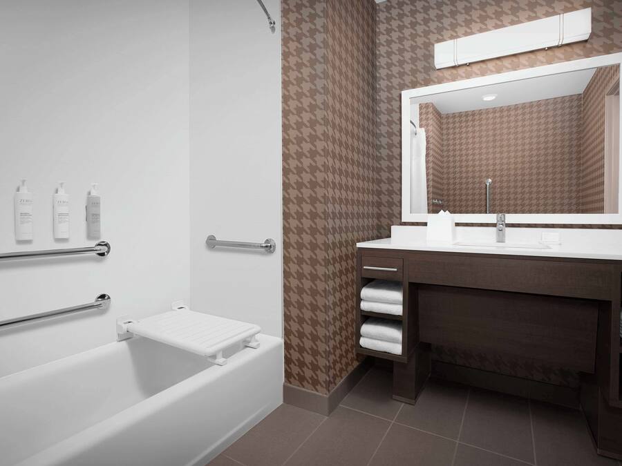 A modern bathroom with a bathtub, a vanity with a mirror, and a towel rack.