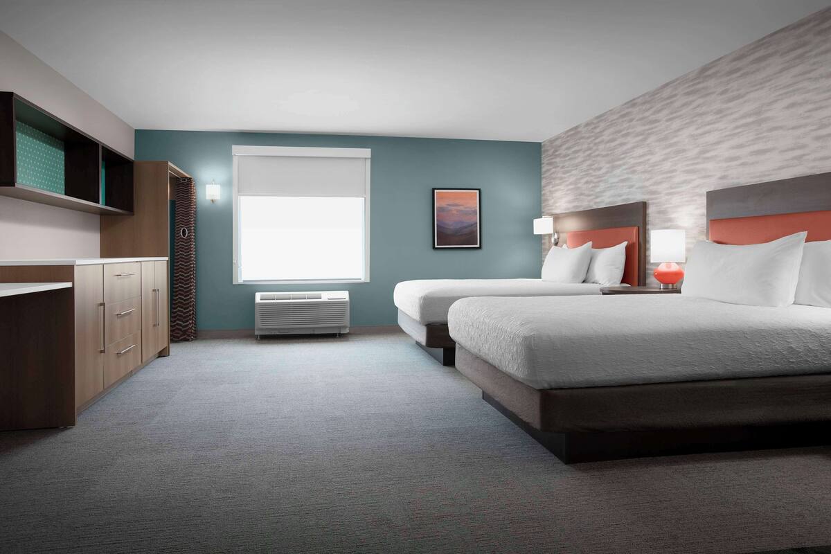 Ein Hotelzimmer mit einem großen Bett, einem Schreibtisch, einem Stuhl und einem Fenster.