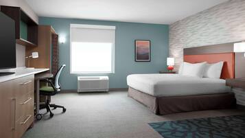 A hotel room with a bed, desk, chair, and a window with blinds.