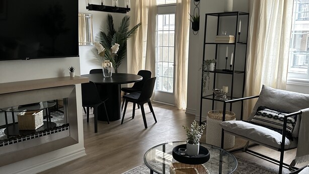 Un salon moderne doté d’un téléviseur à écran plat, d’une table basse ronde, de canapés et d’un coin repas avec une table et des chaises.