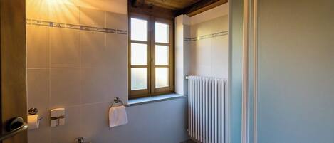 A bathroom with a bidet, a window, and a radiator.
