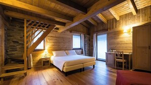 A cozy log cabin bedroom with a bed, a desk, and a chair.