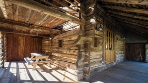 A log cabin interior with a wooden bench, a door, and a window.