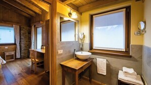 A wooden cabin bathroom with a wooden vanity, a large mirror, a sink, and a window with a view of the mountains.