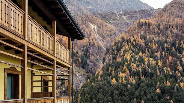 A wooden balcony with a view of a forested mountain range.