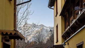 A narrow street with traditional wooden buildings, a mountain backdrop, and a clear sky.