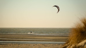 A beach with a person kite surfing and a kite in the air. - Updated Home Walkable to Oceanfront! (Virginia Beach)