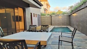 Un jardin avec une piscine, une table et des chaises.
