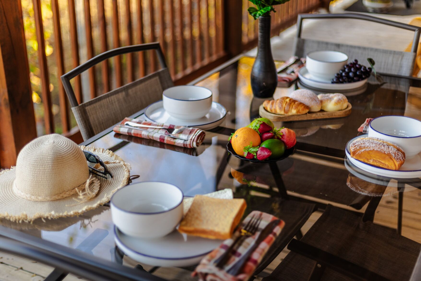 A table set with breakfast items, including bread, fruit, and cups.