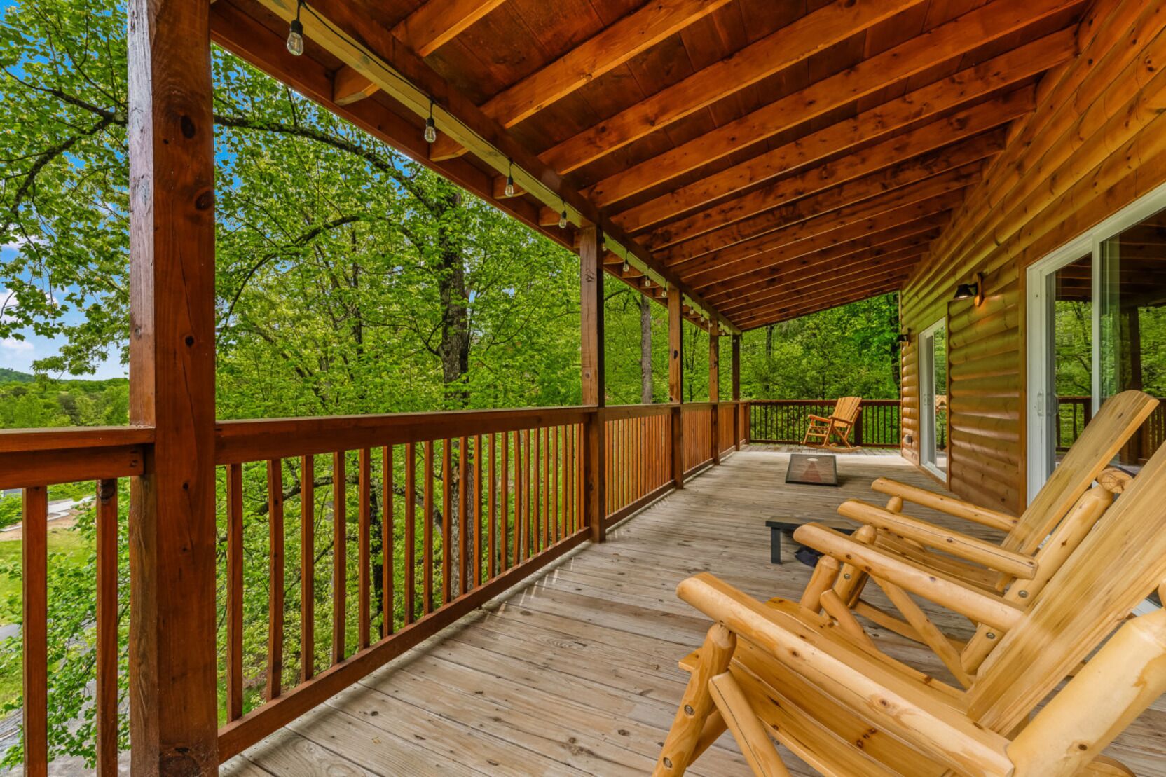 Une terrasse en bois avec une rambarde, des chaises en bois et une table.