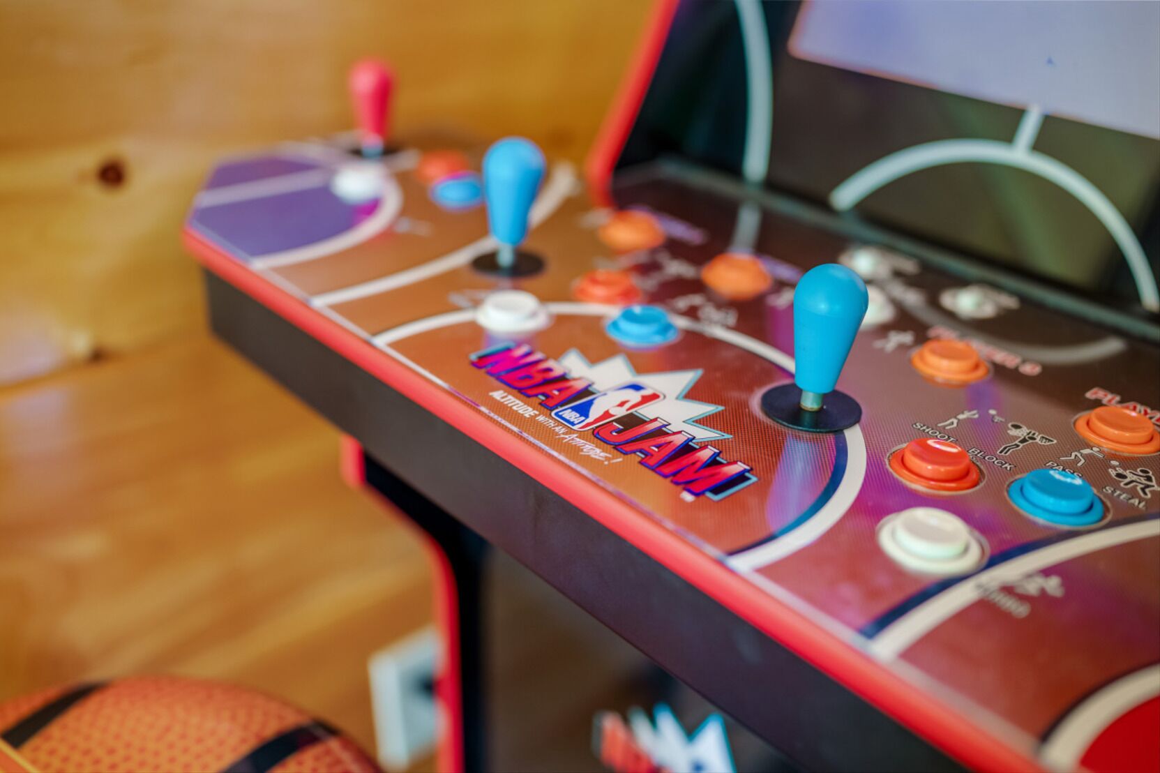 A close-up of a basketball arcade game machine with colorful buttons and the text "NBA JAM" on the side.