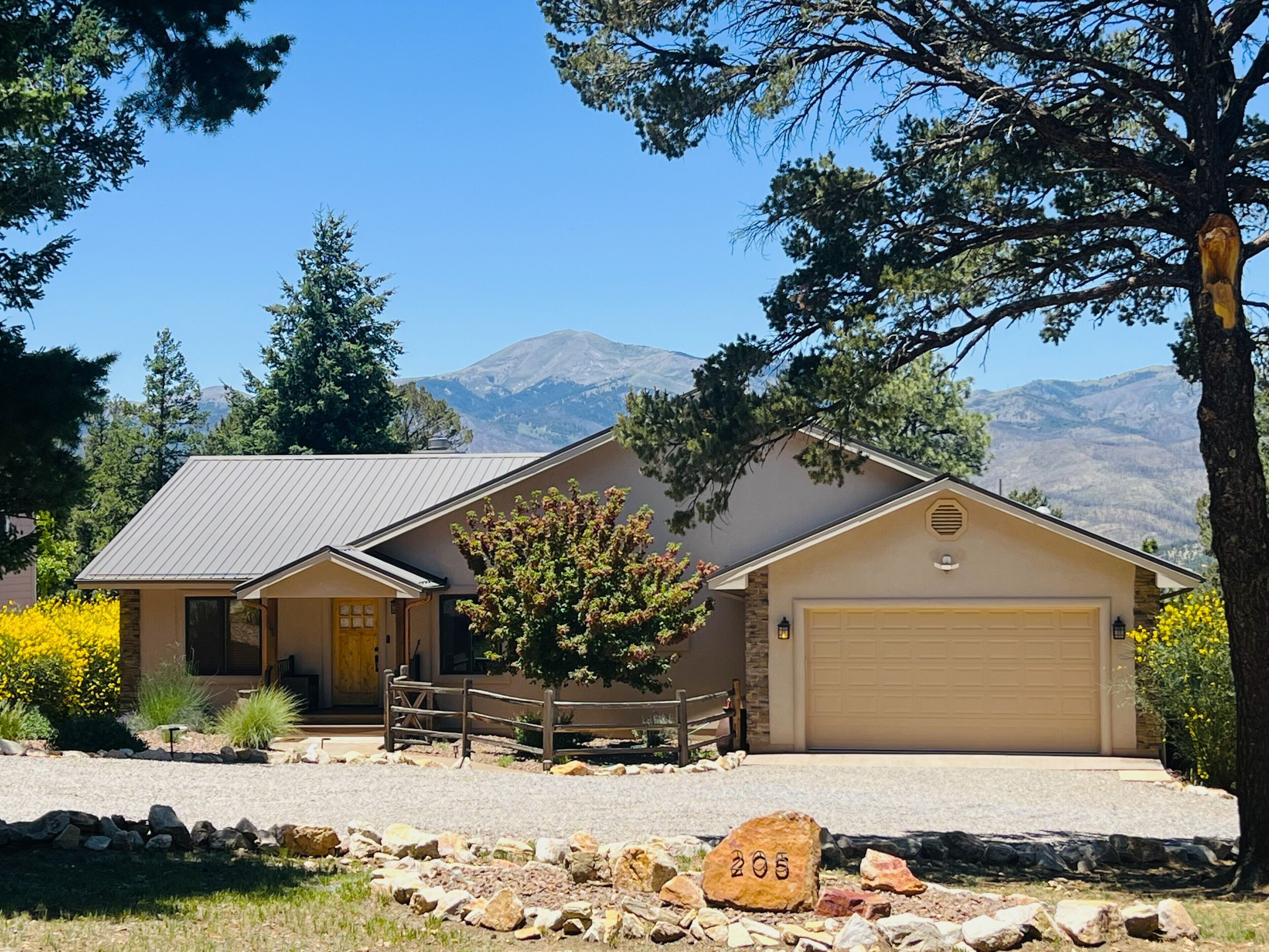 A two-story house with a garage, a stone pathway, and a mountain in the background.