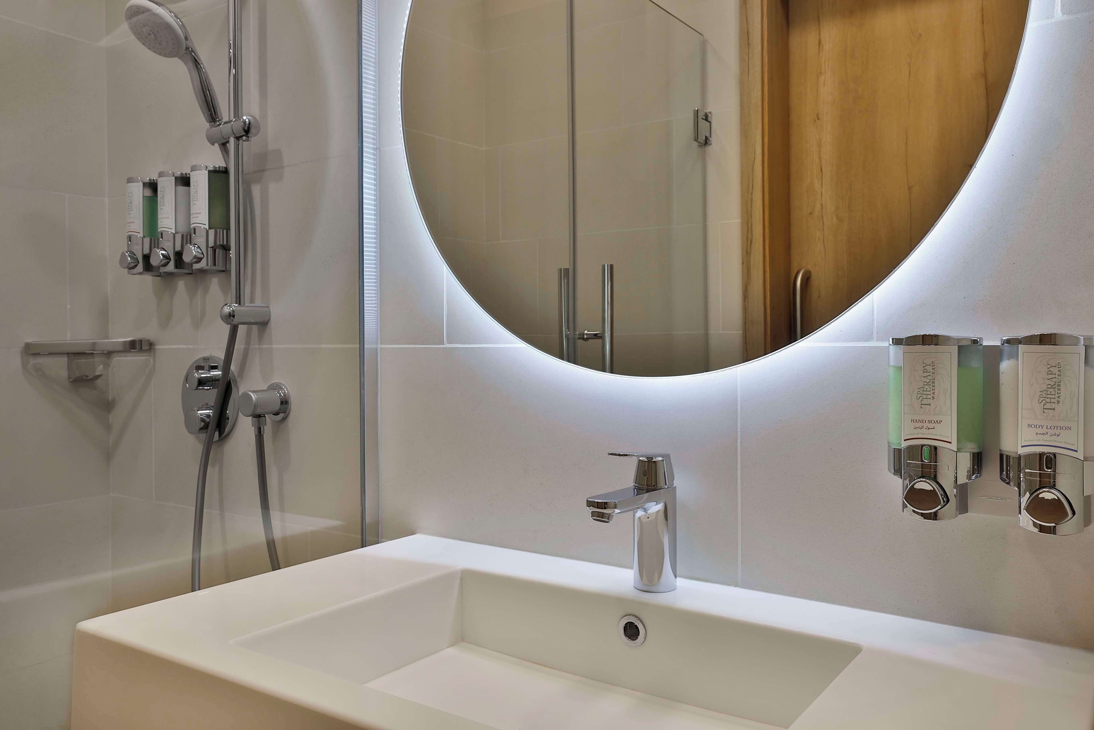 Un baño moderno con un espejo grande, una bañera y una ducha.