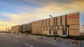 Moderni hotelli, jossa on tasainen julkisivu, useita ikkunoita ja kyltti, josta ilmenee, että se on Hampton-hotelli.
