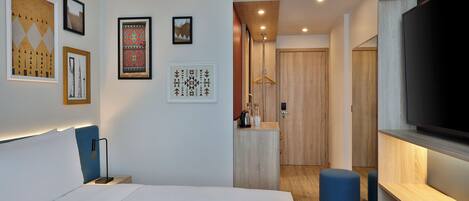 A modern hotel room with a large bed, a TV, and a desk area.