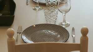 A dining table set with plates, cutlery, and glasses. - Cristina Apartment - Near the Beach (Armação de Pêra)
