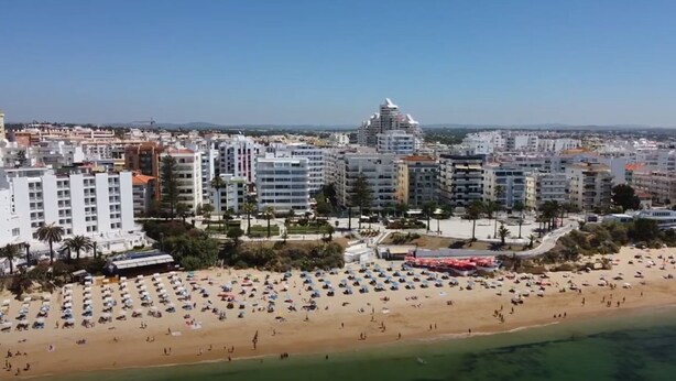 A coastal cityscape with a beach, multiple high-rise buildings, and a prominent tower. - Cristina Apartment - Near the Beach (Armação de Pêra)