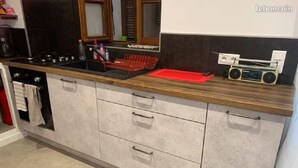 A kitchen with a wooden countertop, a built-in stove, and a radio.