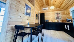 A wooden interior with a dining area, kitchen, and a poster on the wall. - Sleeping Lion Casita in Fort Davis, Texas. Explore The Davis Mountains and area. (Fort Davis)