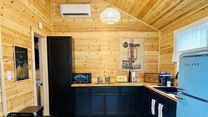 A compact kitchen with wooden walls, a black countertop, and a blue refrigerator. - Sleeping Lion Casita in Fort Davis, Texas. Explore The Davis Mountains and area. (Fort Davis)