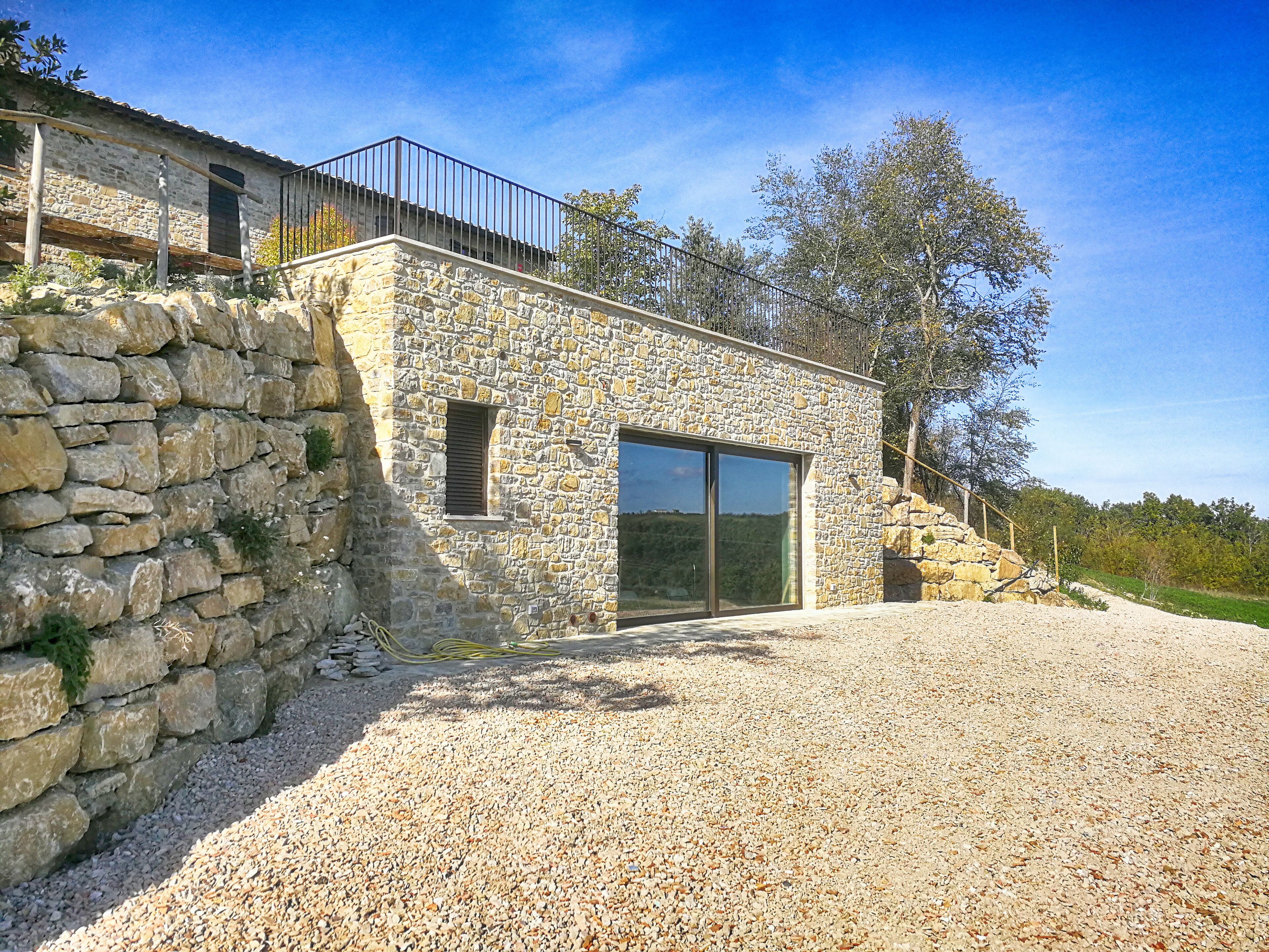 A stone building with a gravel driveway and a metal railing.