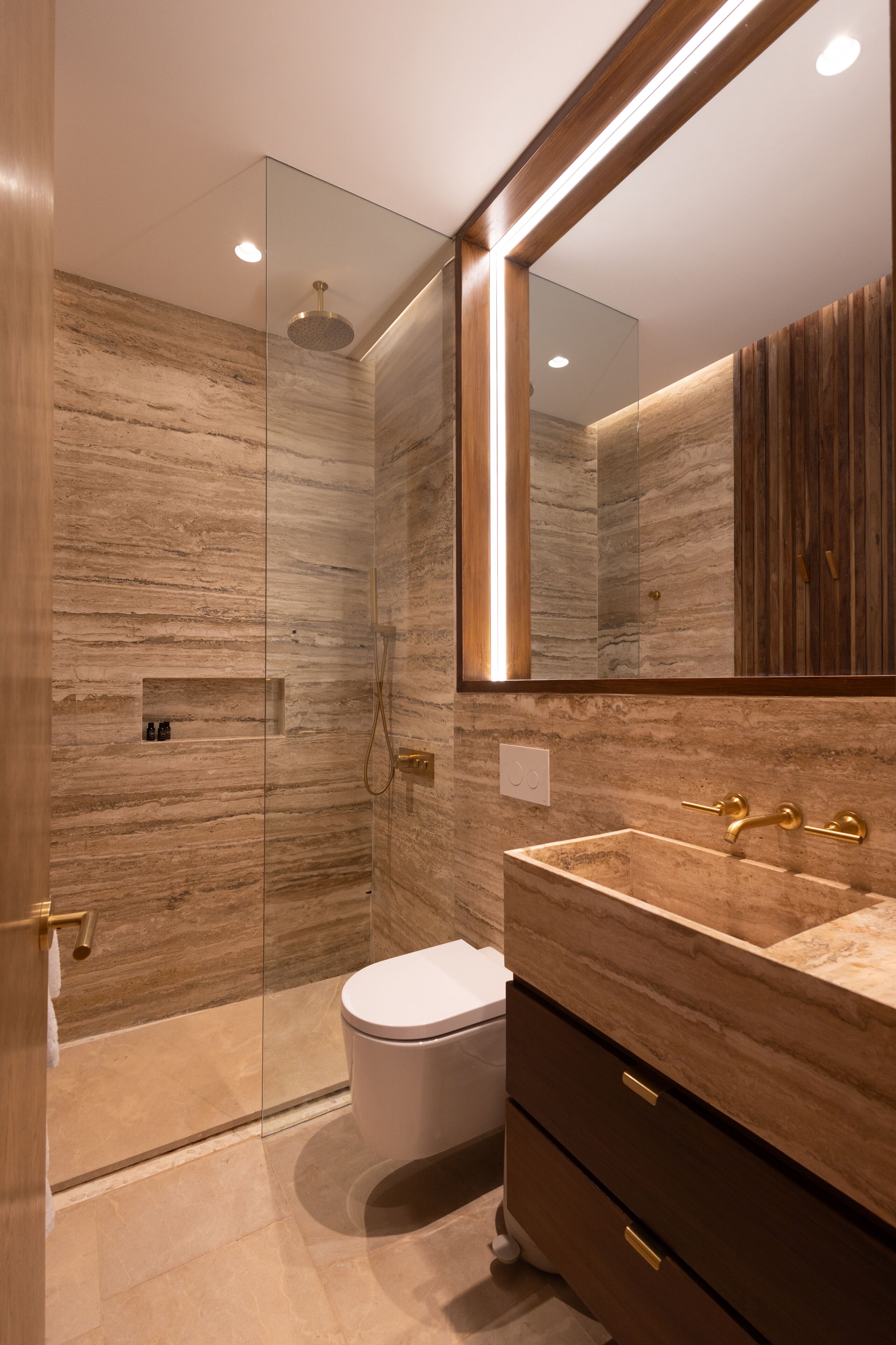 A modern bathroom with a glass-enclosed shower, a marble vanity, and a large mirror.