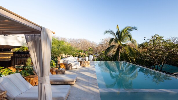 A poolside area with a covered seating area, a clear pool, and surrounding greenery. - Silvestre Nosara, Hotel & Residences (Nosara)