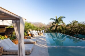A poolside area with a covered seating area, a clear pool, and surrounding greenery. - Silvestre Nosara, Hotel & Residences (Nosara)